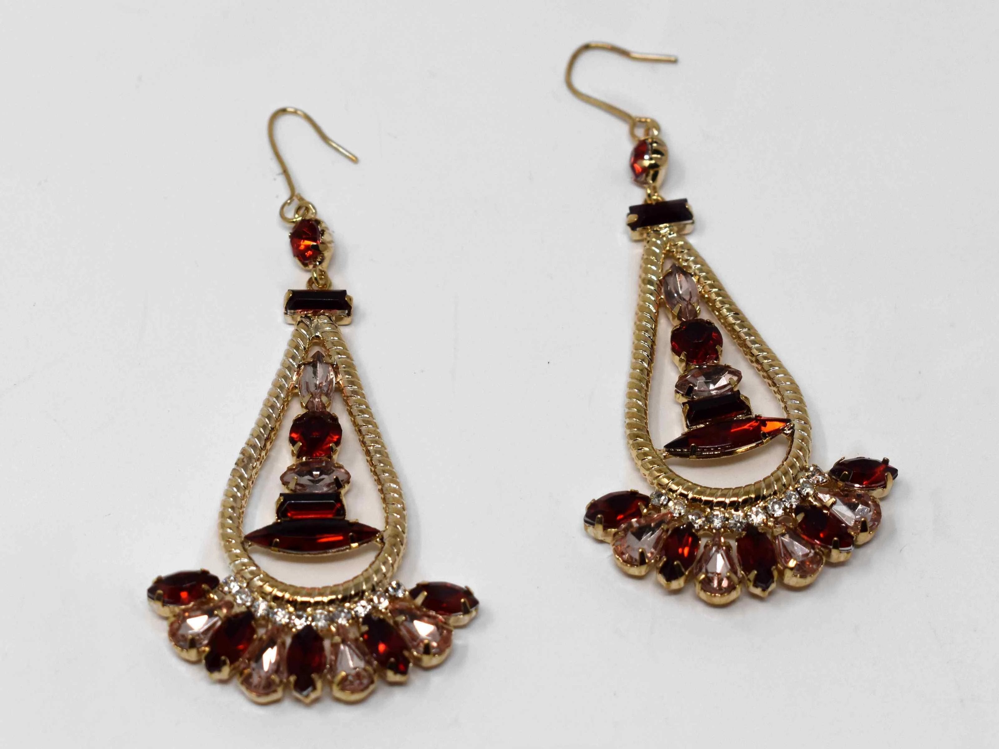 Anemone is a gold with a red and clear stone eye catching drop , dangle style earring. It comes with a fish hook clasp and is 3 inches in length.