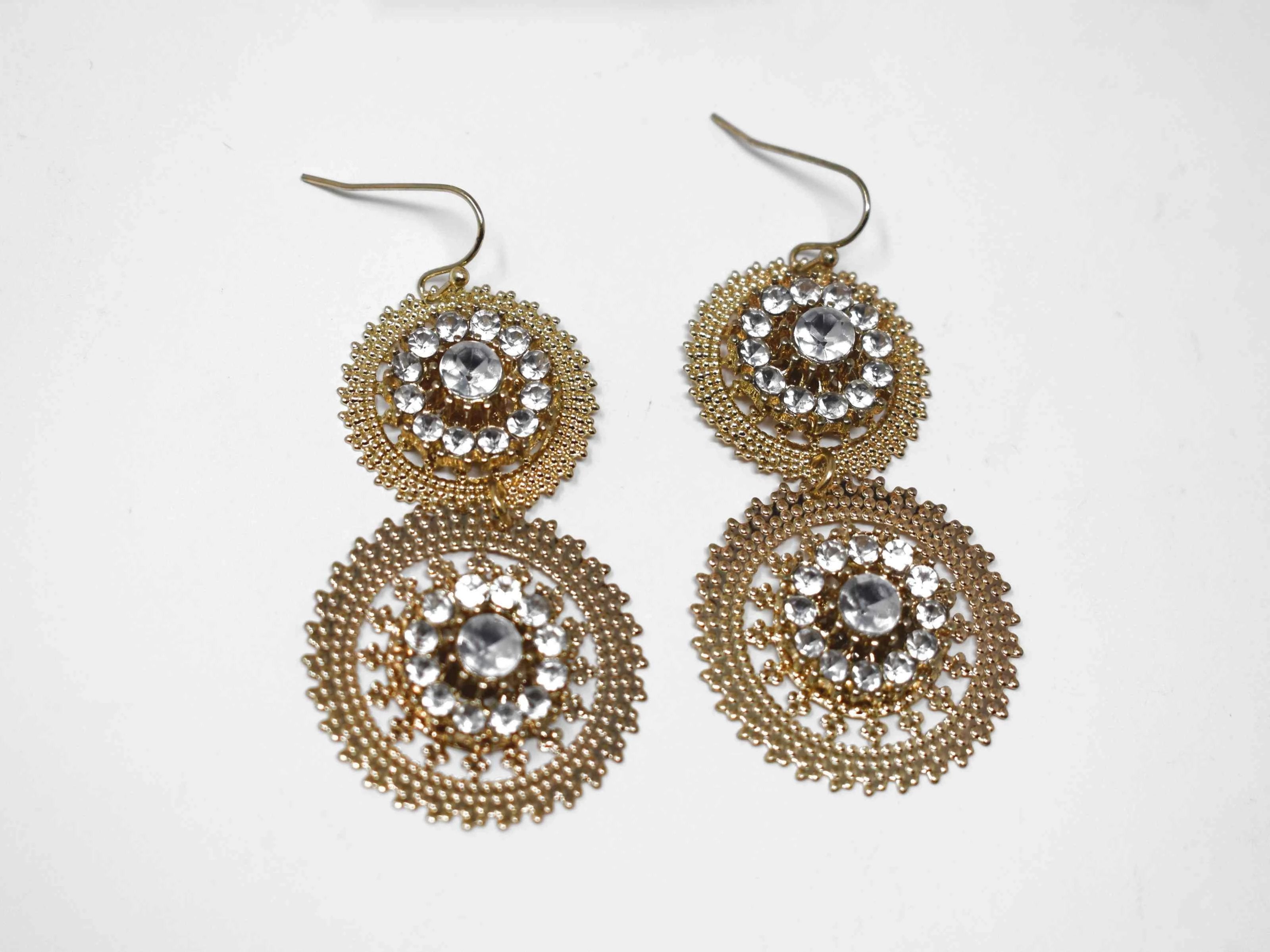 Our Aster is a chic gold tone drop dangle style earring accented with clear stones. It measures around 2 1/2" in length.