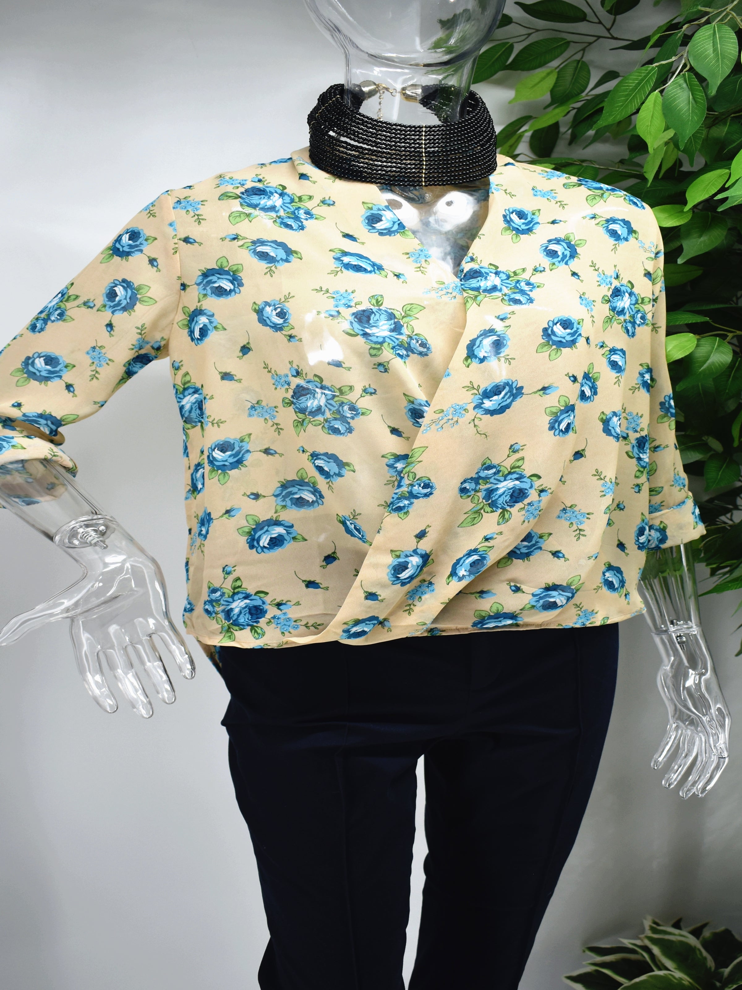 Our Baileil floral blouse will let them notice you when you walk into the room. Our Baileil blouse is a beige lap front top with blue floral prints. 