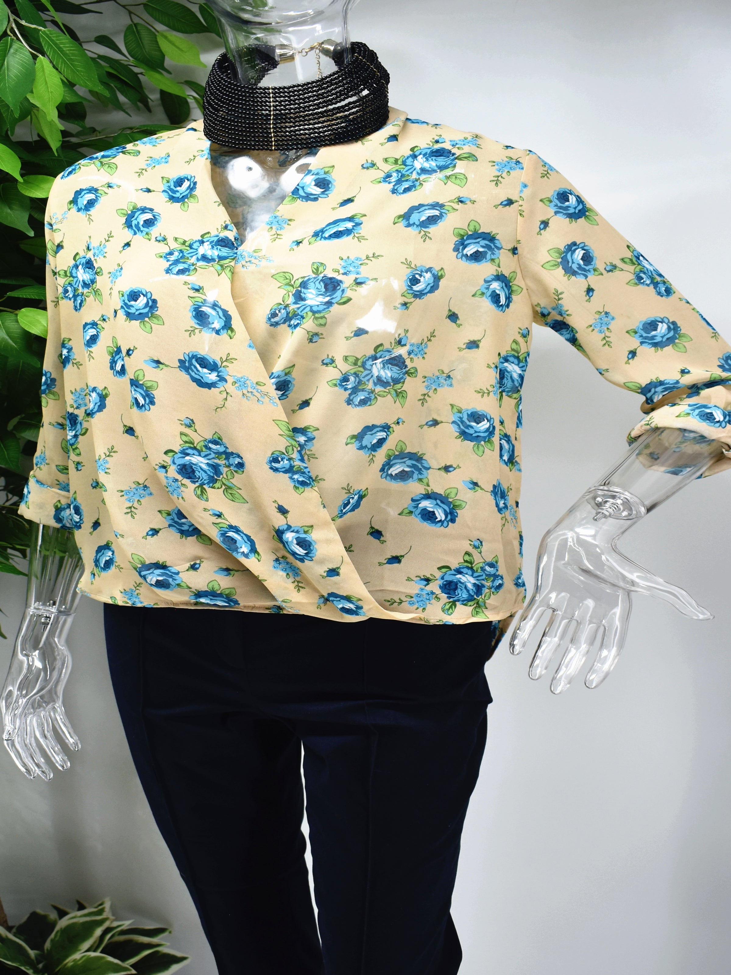 Our Baileil floral blouse will let them notice you when you walk into the room. Our Baileil blouse is a beige lap front top with blue floral prints. 