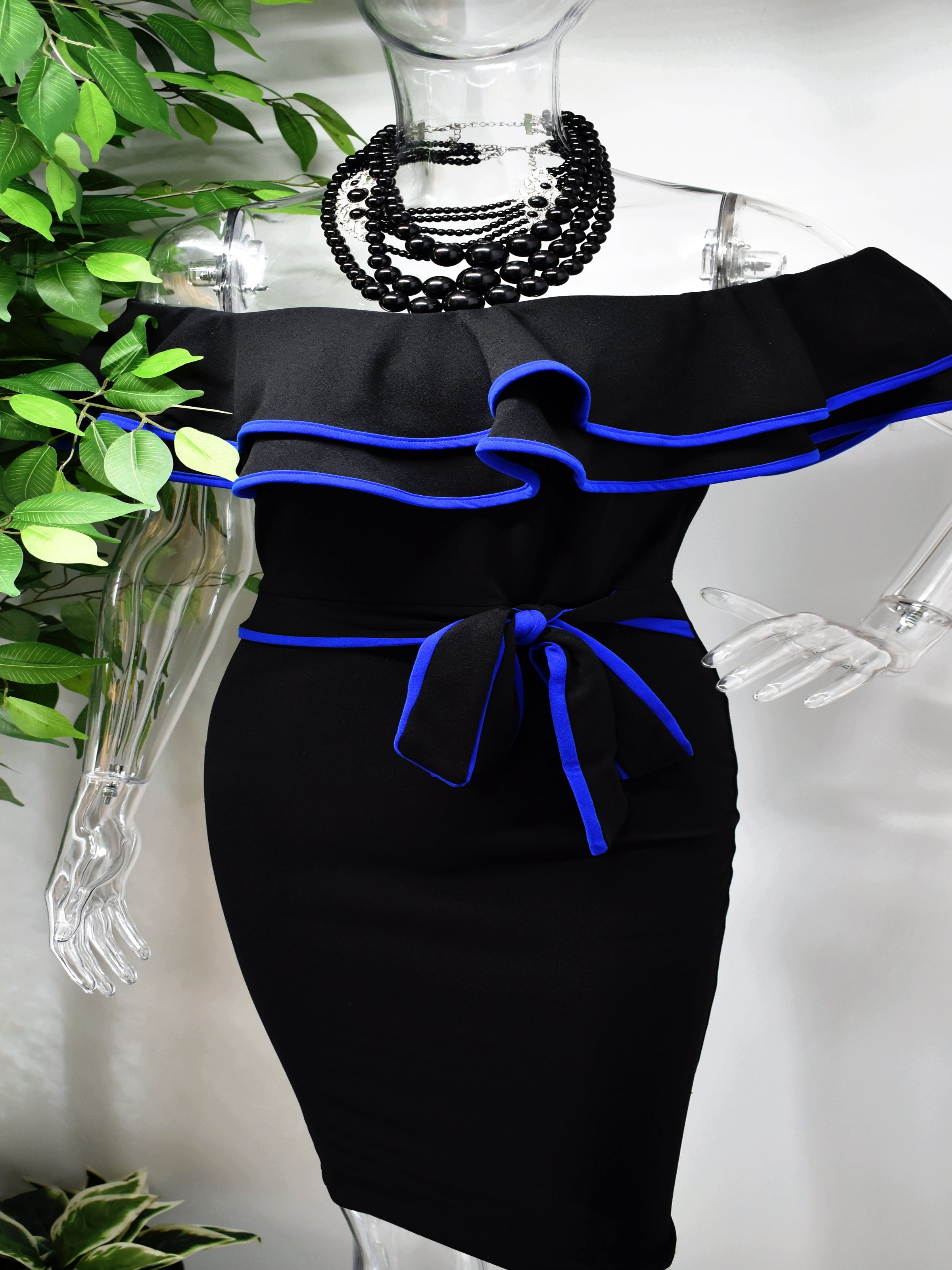 Our Berdine Black Midi Dress is picture perfect with its off the shoulder ruffled neckline and fitted bodice. The ruffled neckline and belted waist is piped with a beautiful blue.