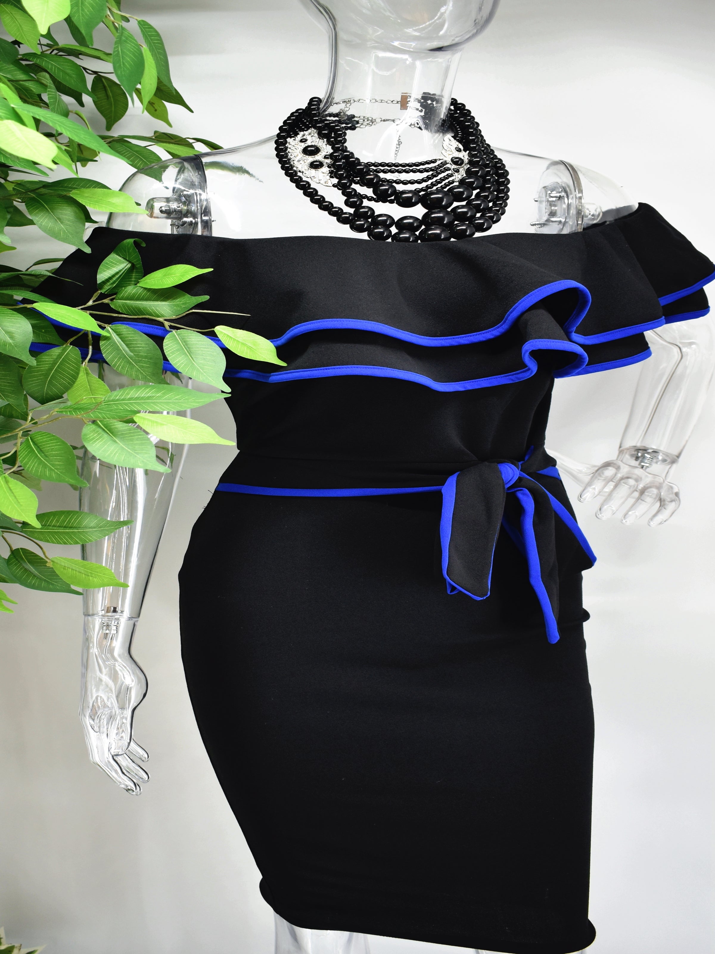 Our Berdine Black Midi Dress is picture perfect with its off the shoulder ruffled neckline and fitted bodice. The ruffled neckline and belted waist is piped with a beautiful blue.