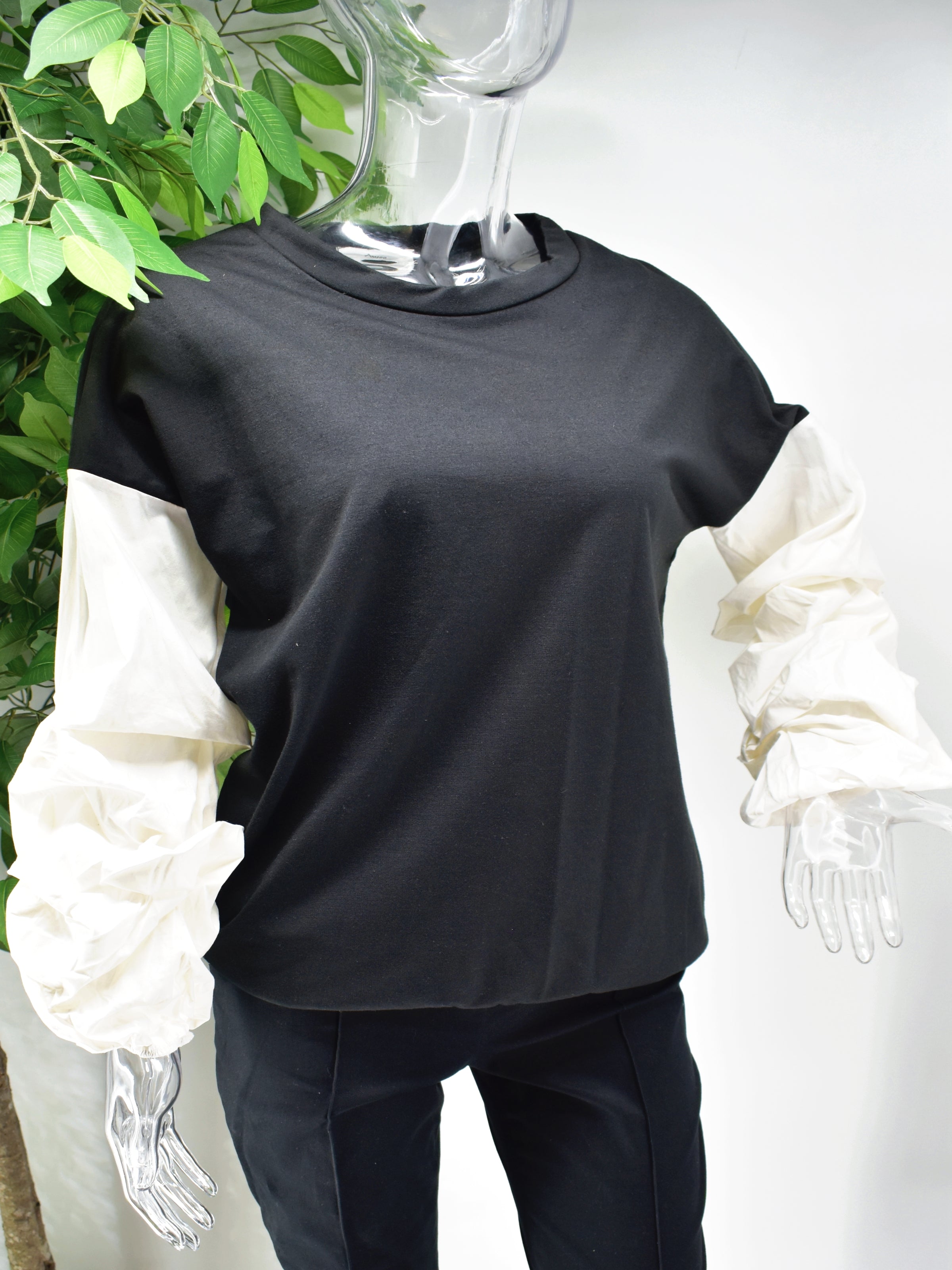 Let's Reinvent the sweater with our Bianey Black sweater top.  Our Bianey top is a black sweater top with a white puffed rouged sleeve.