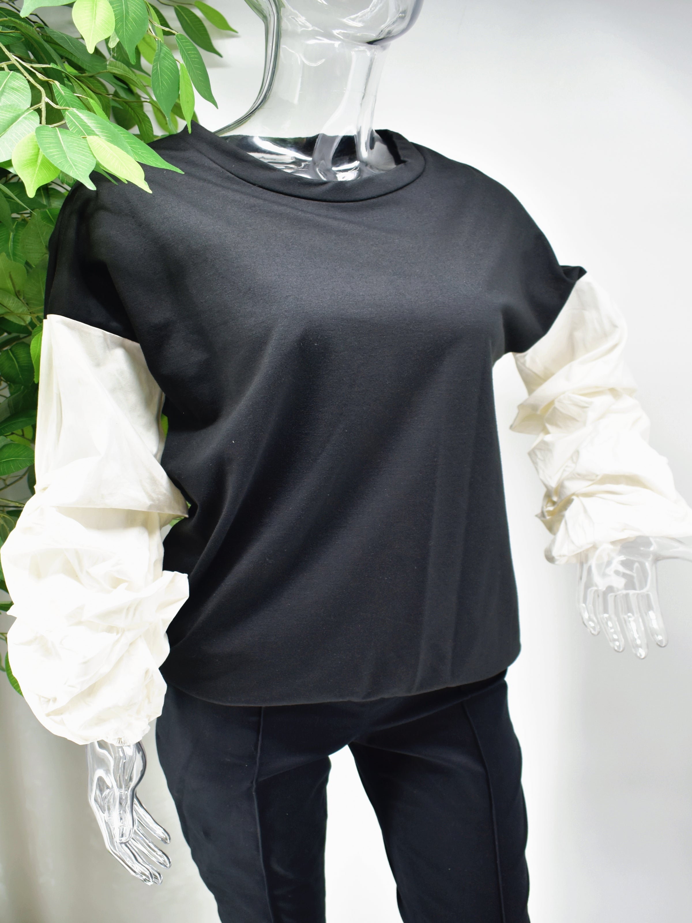 Let's Reinvent the sweater with our Bianey Black sweater top.  Our Bianey top is a black sweater top with a white puffed rouged sleeve.