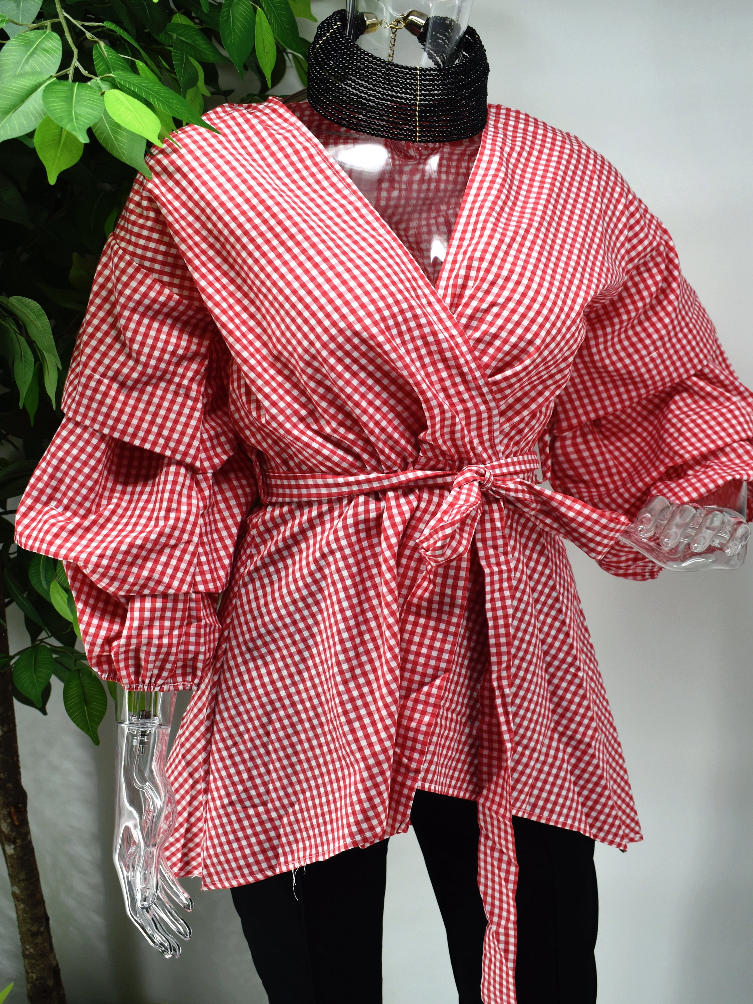 A classic print meets a modern design with our Birdina red and white gingham print top. Our Birdina is full of style and pizzaz. It has a v-neckline, ruffled puffed sleeve and an uneven hem. The design is completed with a tied cinched waist.