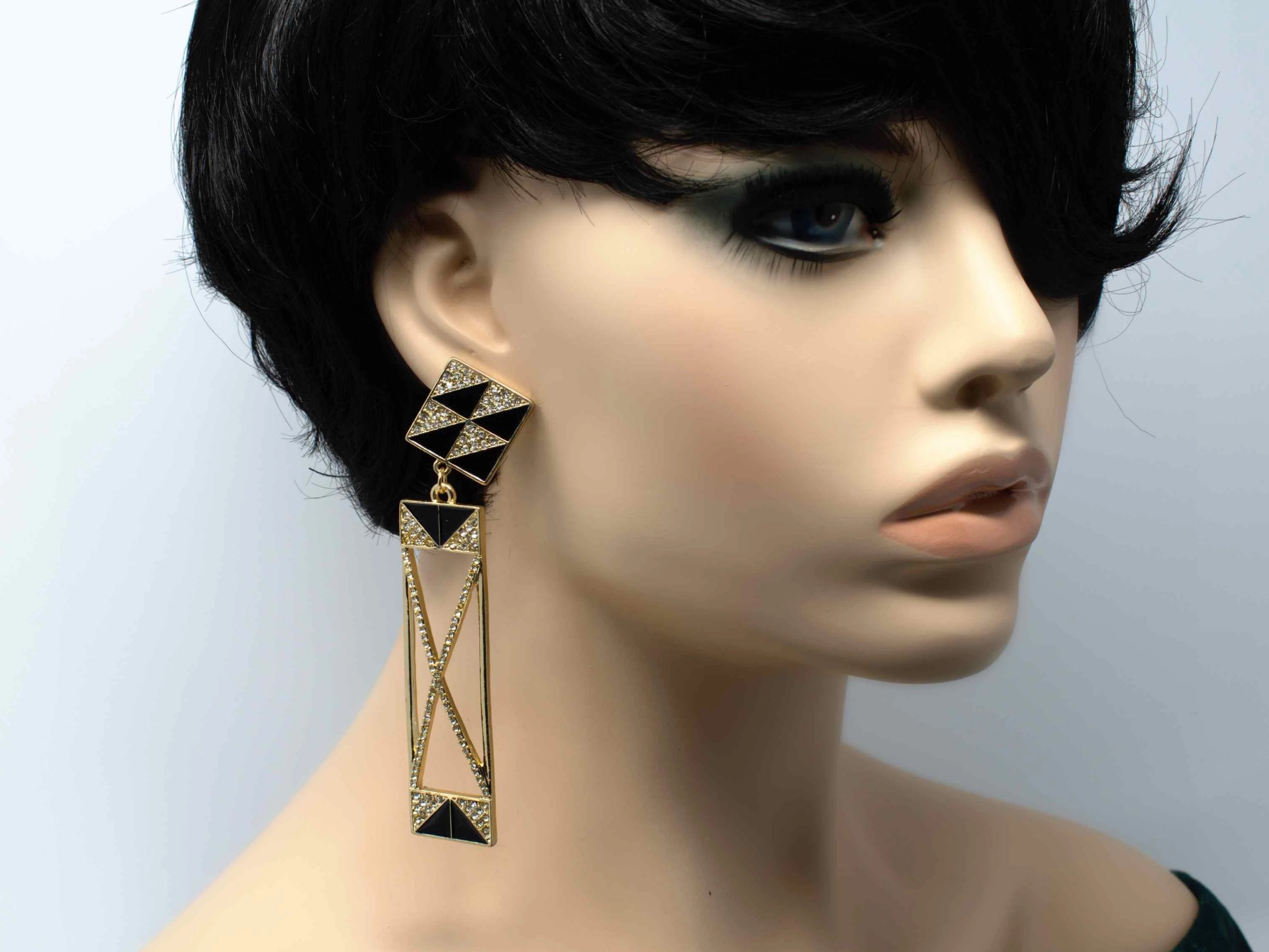 A gold dangle drop chandelier earring with stone accents and a push back clasp.