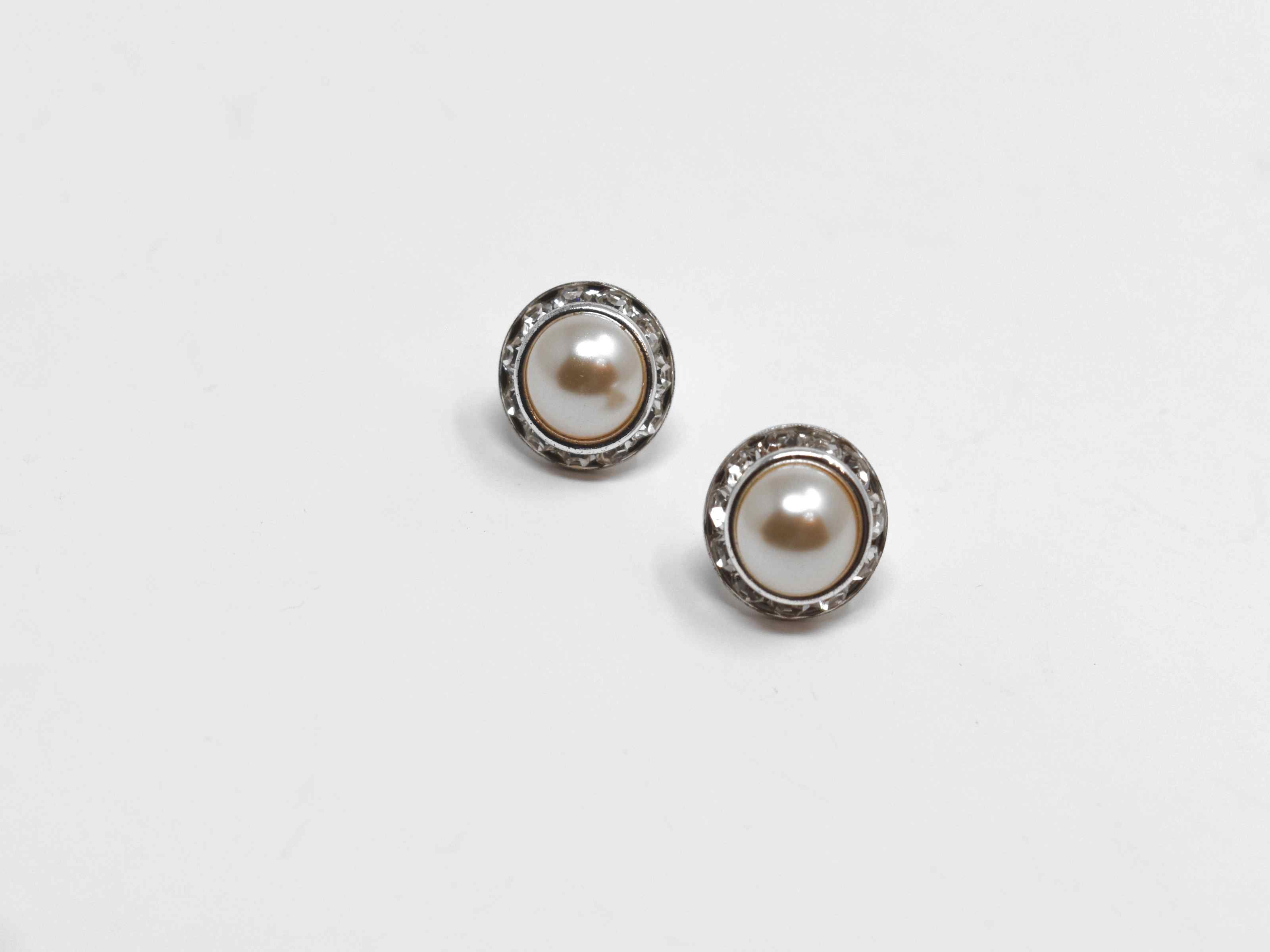 We would love for you to enjoy our delicate but chic calendula pearl knob earrings. These earrings have a champagne center pearl surrounded by a halo of stones. They are a 1/2 inch in length with a push back clasp.