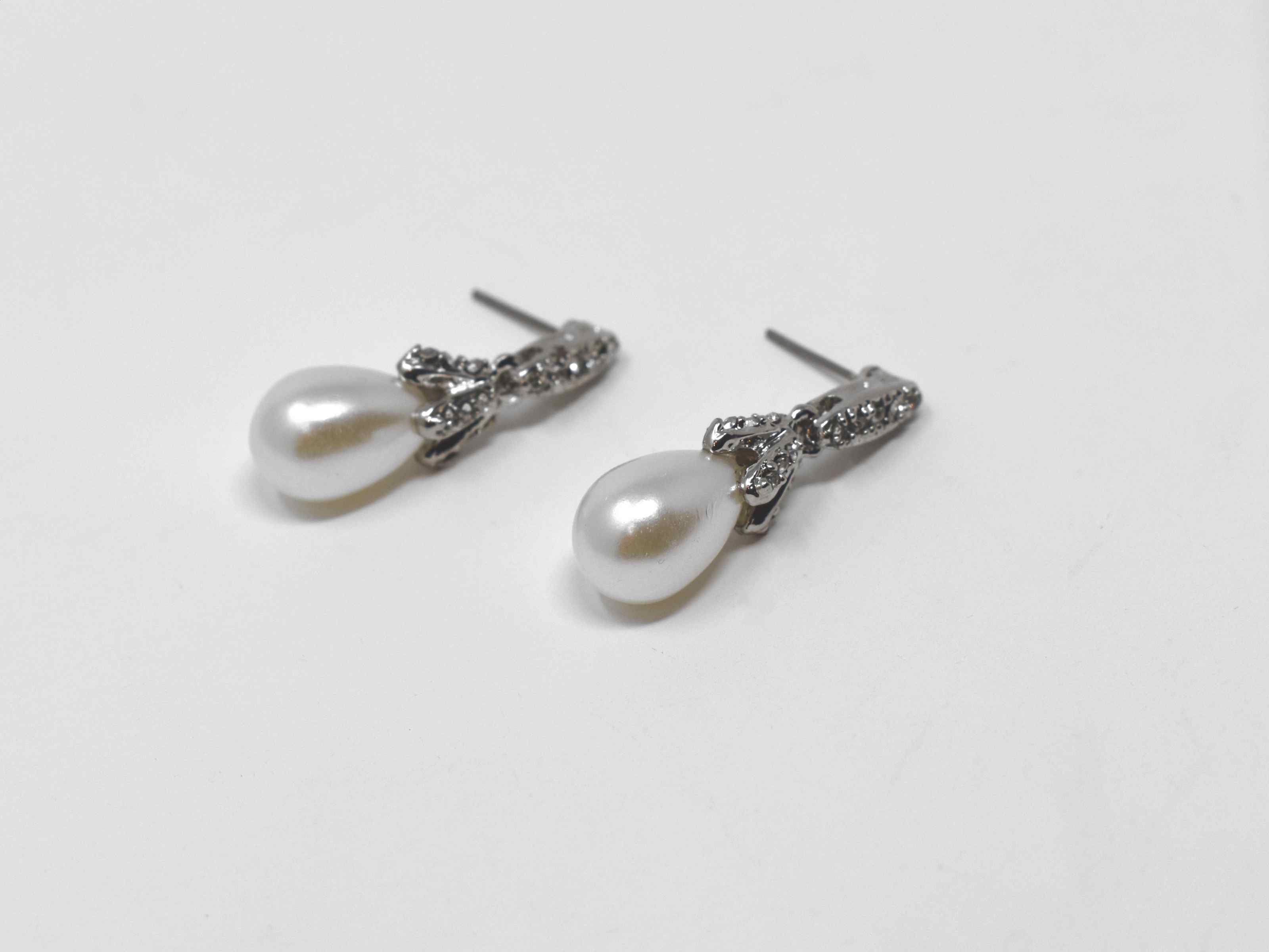 Our Daffodil earrings are a modern take on a classic staple. These silver dangle knob earrings has a pearl core with an accent of stones. It is  1 1/4 inches in length with a push back clasp.