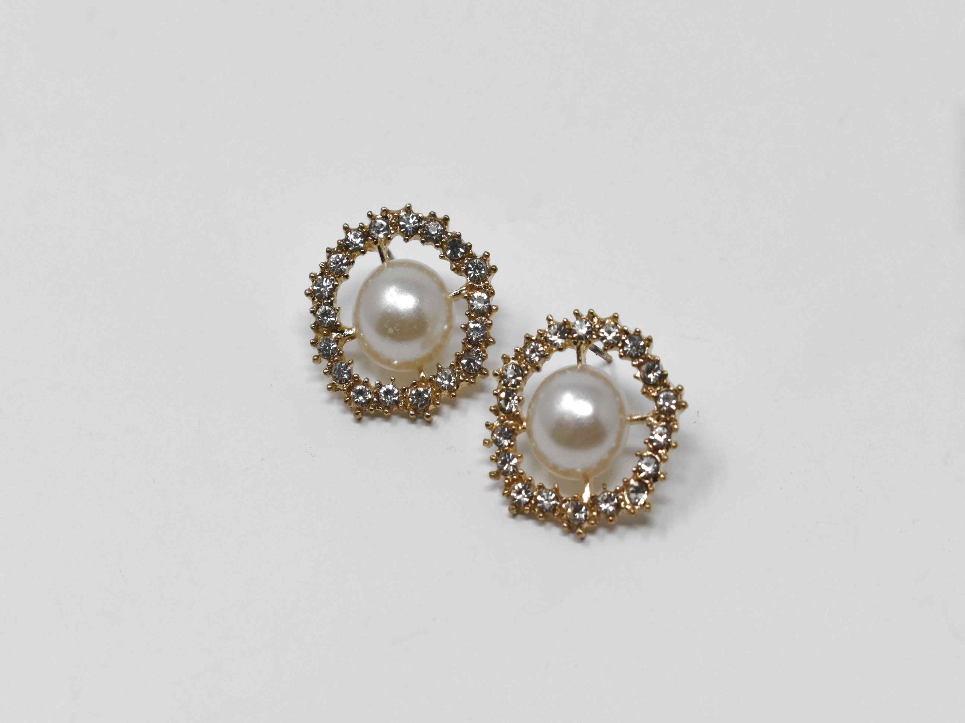 Our dietes earrings are a must have staple with a burst of sparkle. These earrings are a gold tone with a pearl core surrounded by a beautiful halo of stones. They are 3/4 inches in length with a push back clasp.