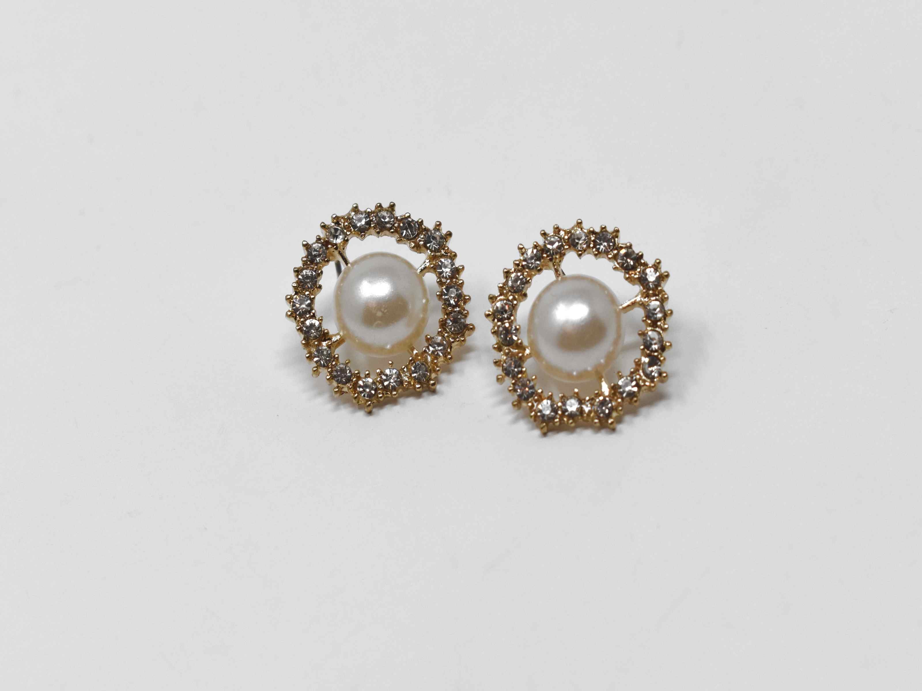 Our dietes earrings are a must have staple with a burst of sparkle. These earrings are a gold tone with a pearl core surrounded by a beautiful halo of stones. They are 3/4 inches in length with a push back clasp.