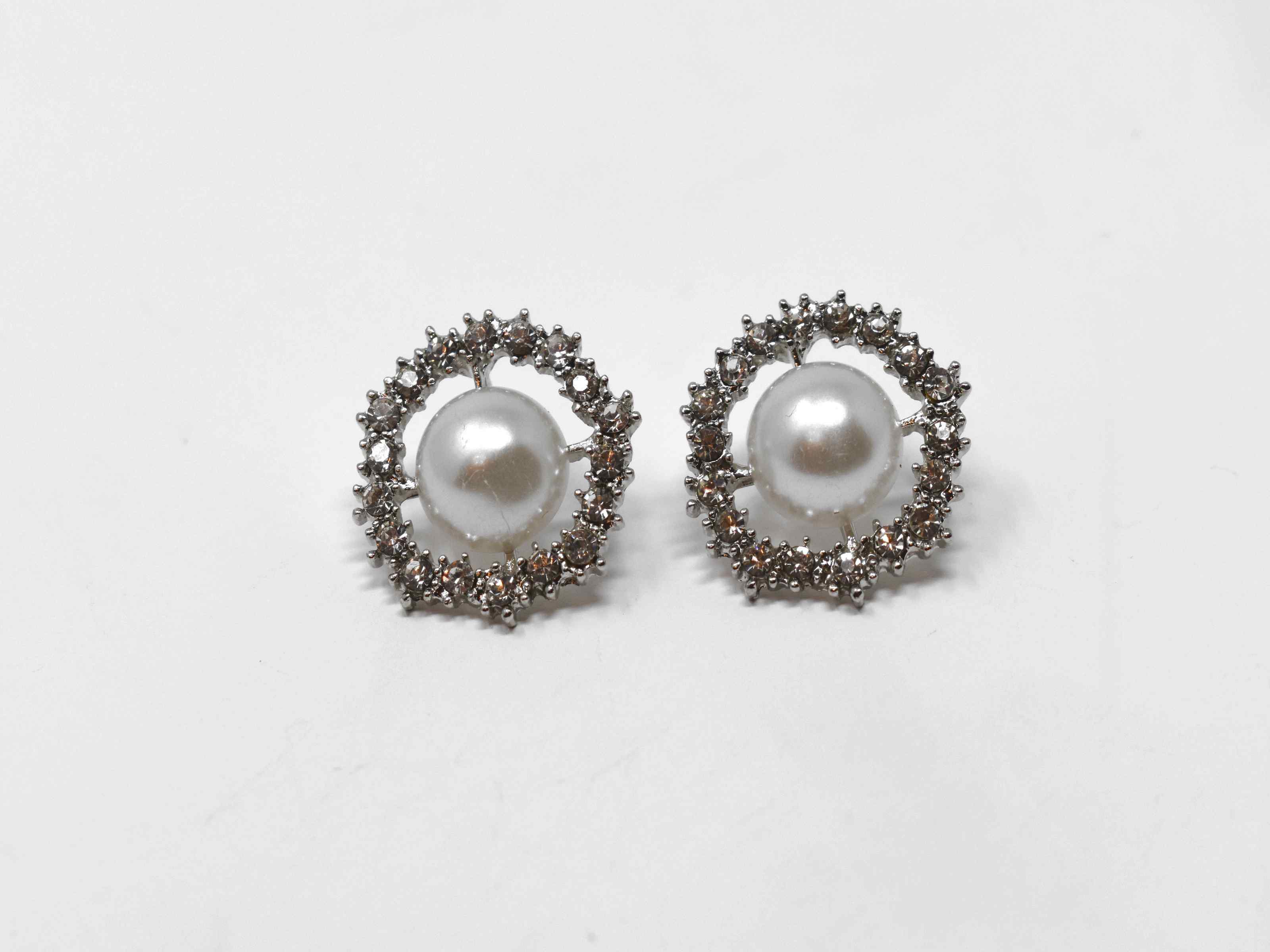Our dietes earrings are a must have staple with a burst of sparkle. These earrings are a silver tone with a pearl core surrounded by a beautiful halo of stones. They are 3/4 inches in length with a push back clasp.