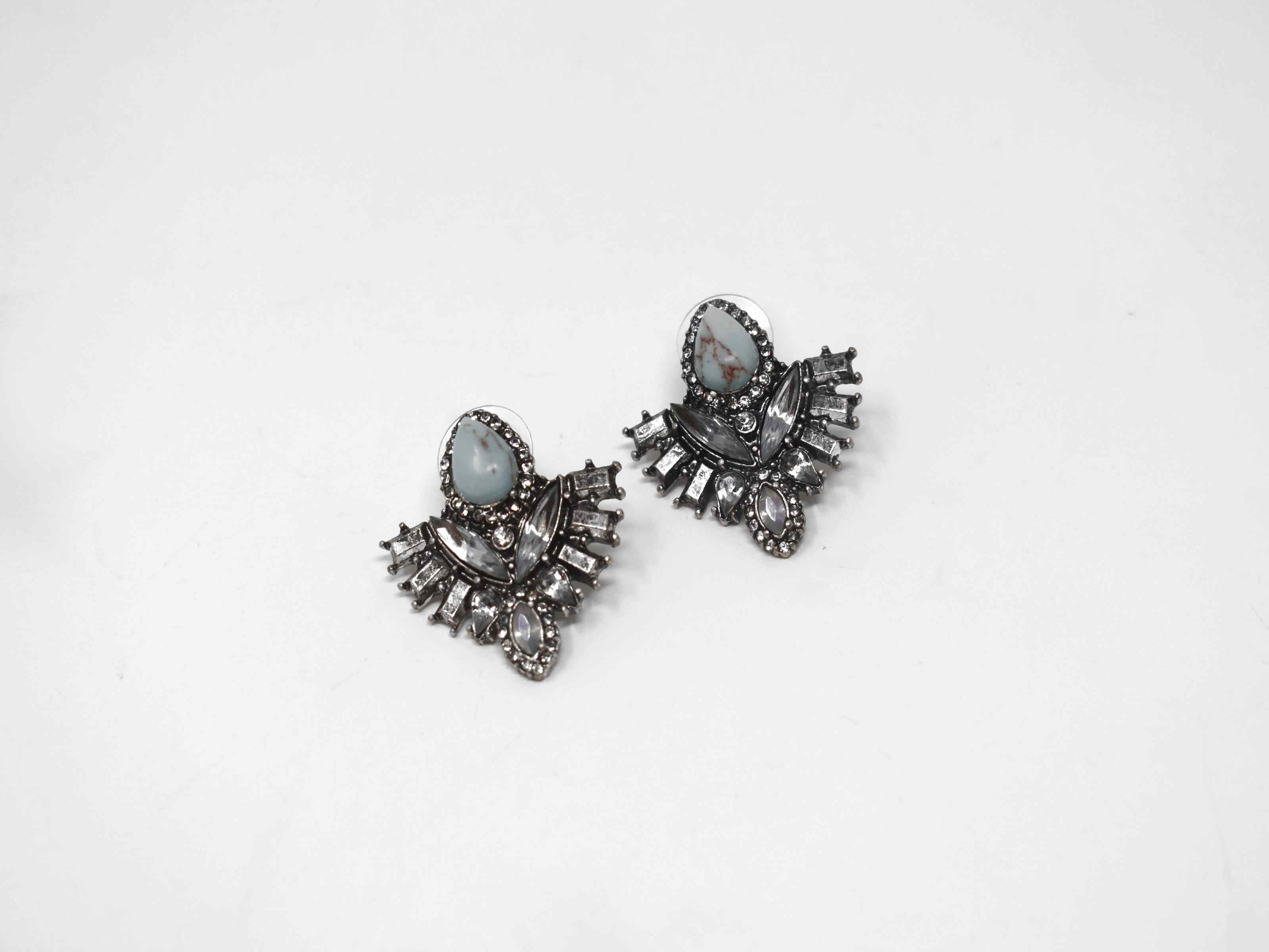Show them who is the boss while making a statement with our Dutch iris earrings. These beauties are a antique shade of silver with iridescent stones surrounding a core turquoise stone. It has a push back clasp and measures 1 inch in length.