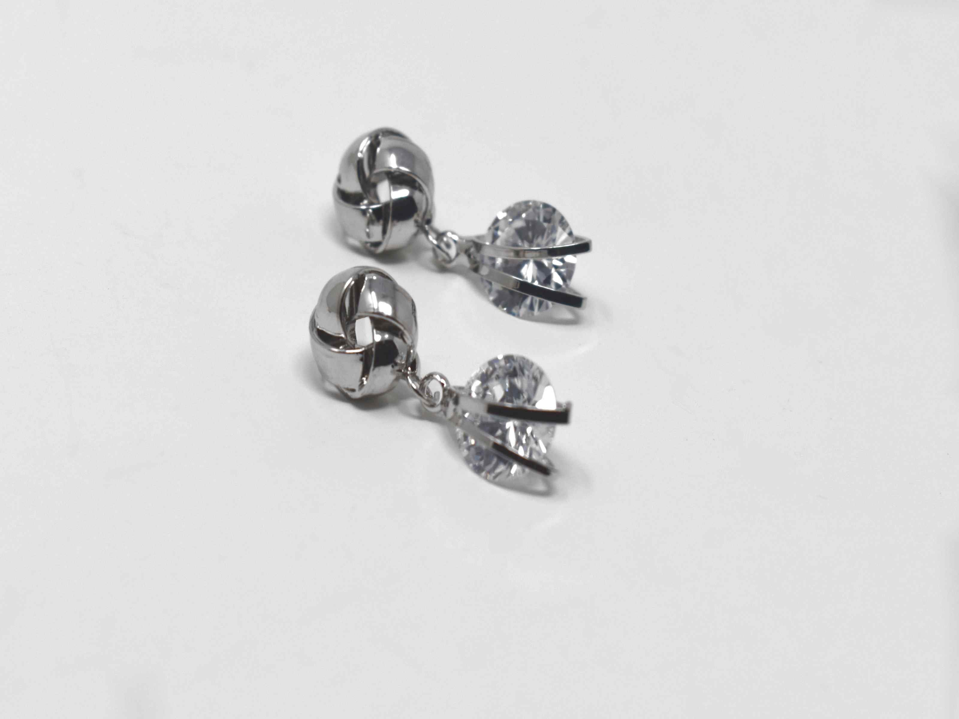 Our Erica earrings are so delicate and chic! These little silver beauties are the perfect knob chandelier earrings with a knot design and a drop dangle stone. It has a push back clasp and is 1 inch in length.