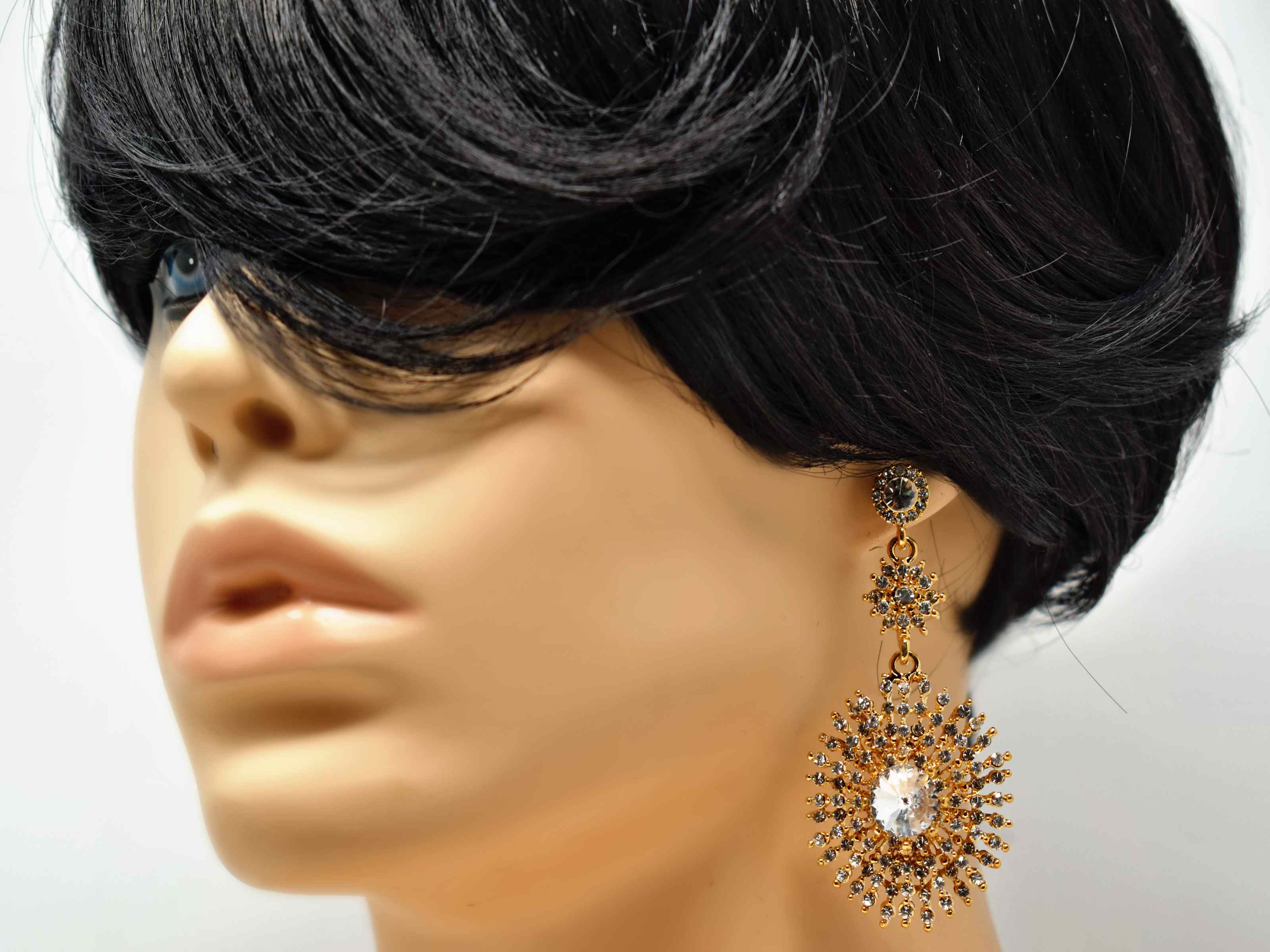 Show off and dazzle with these Gerbera gold dangle earrings. These earrings have a starburst of stones design with a push back clasp and is 3" in length. 