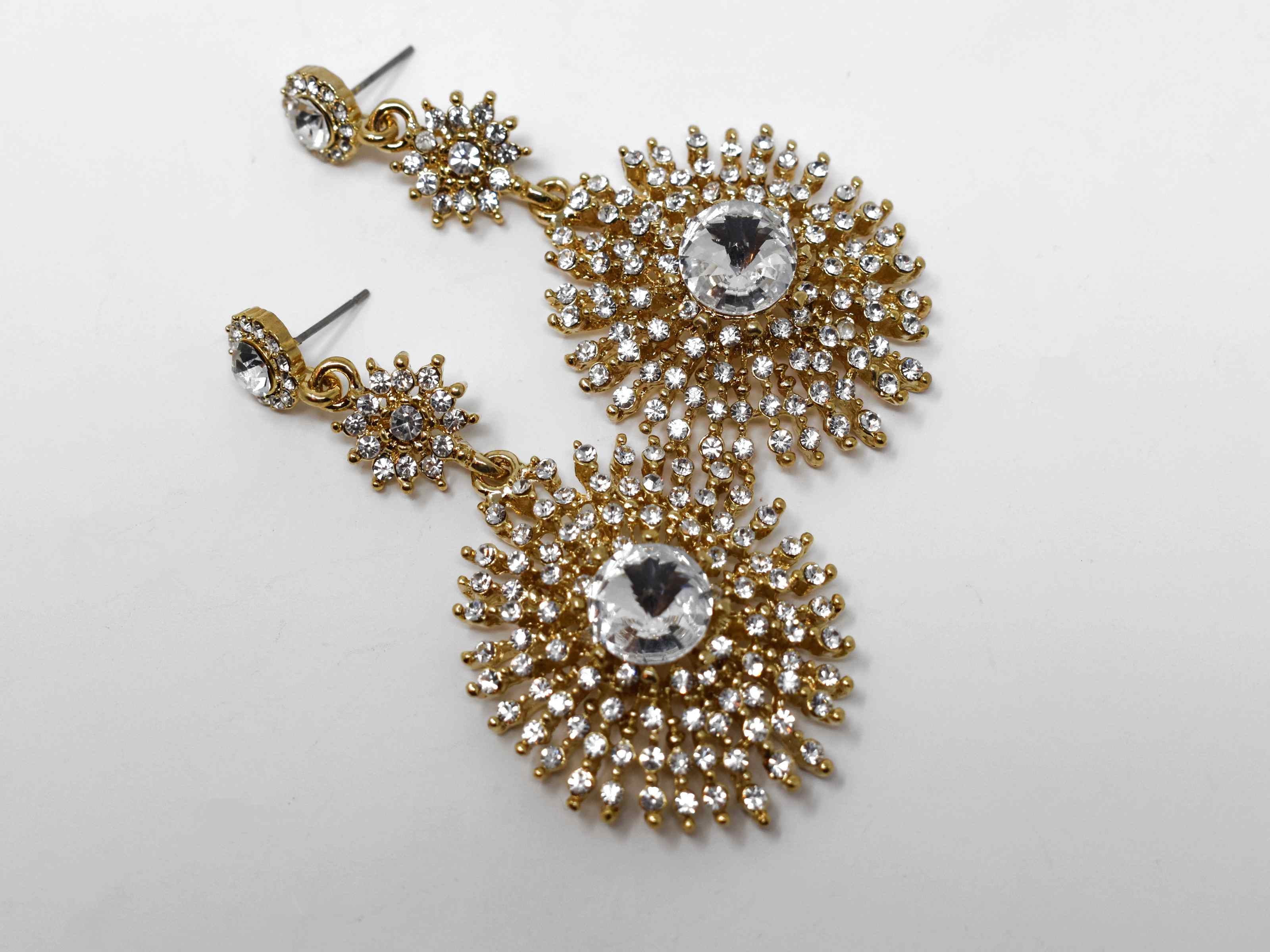 Show off and dazzle with these Gerbera gold dangle earrings. These earrings have a starburst of stones design with a push back clasp and is 3" in length. 