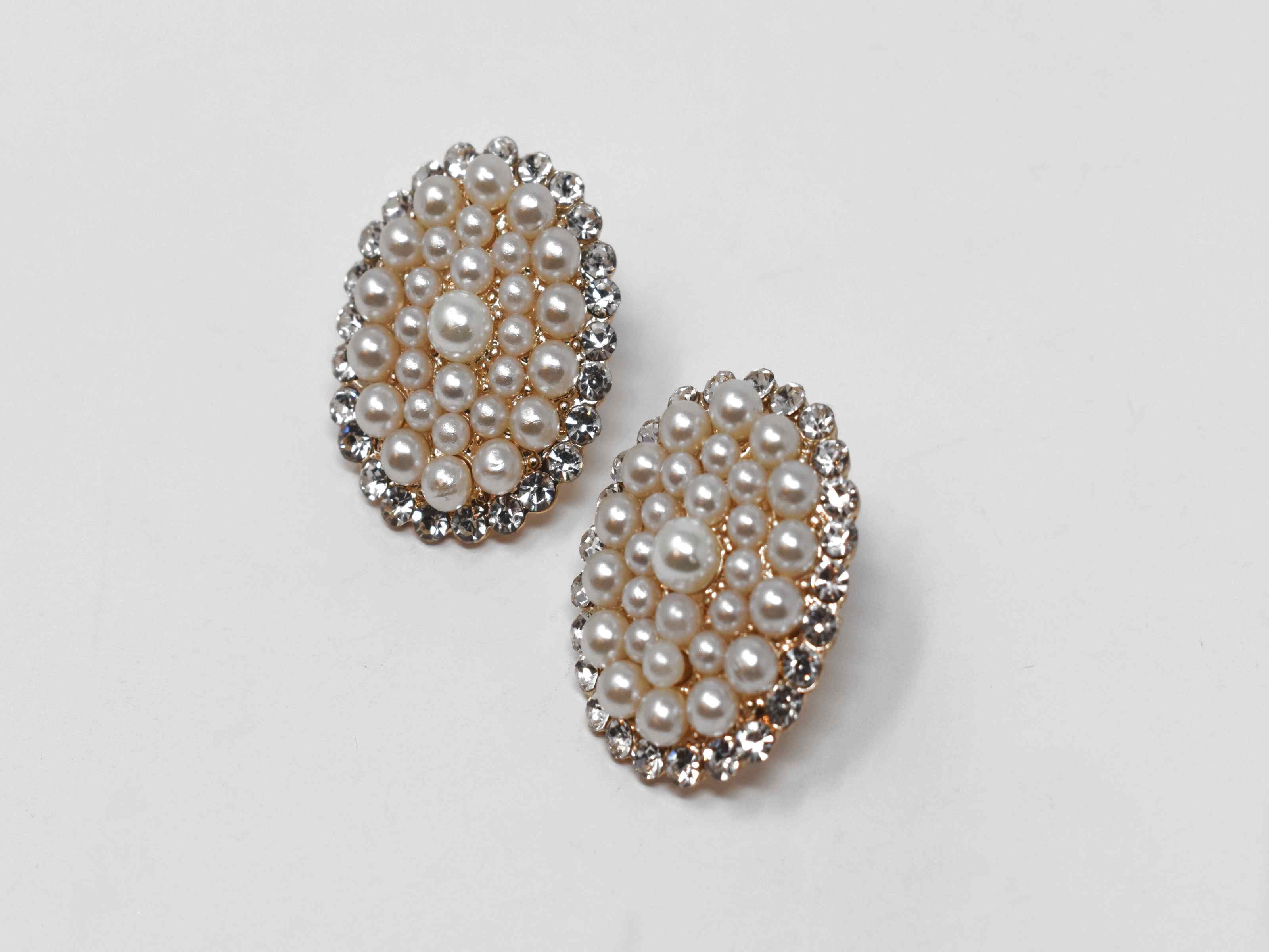 Our adorable Hosta knob earrings is the perfect addition to your wardrobe. Its oval shape is covered in pearl clusters and and has a gold tone with a push back clasp.