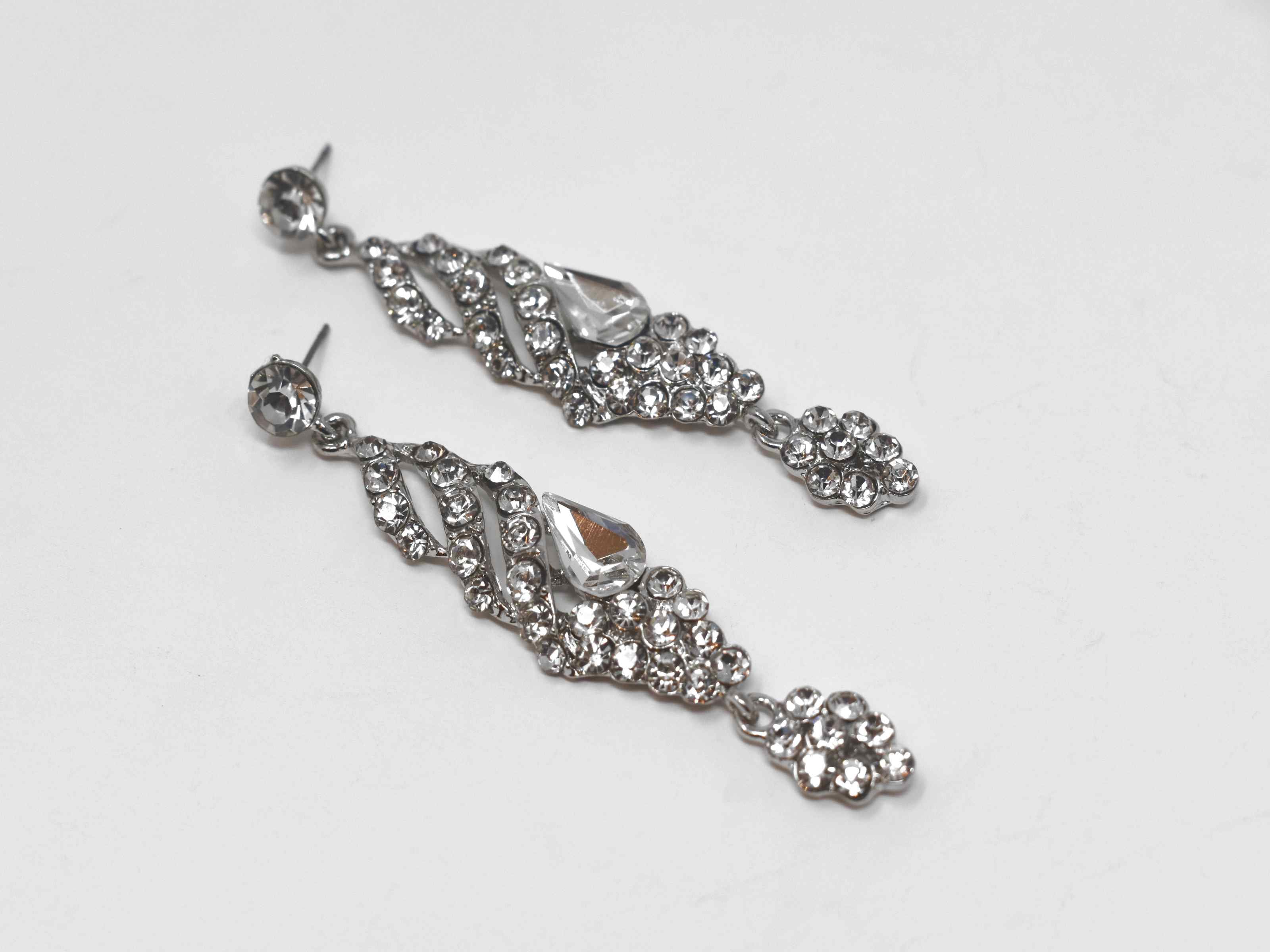 These formal silver earrings are a classic addition to your outfits. They are 3 inches in length and encrusted with clear stones. 