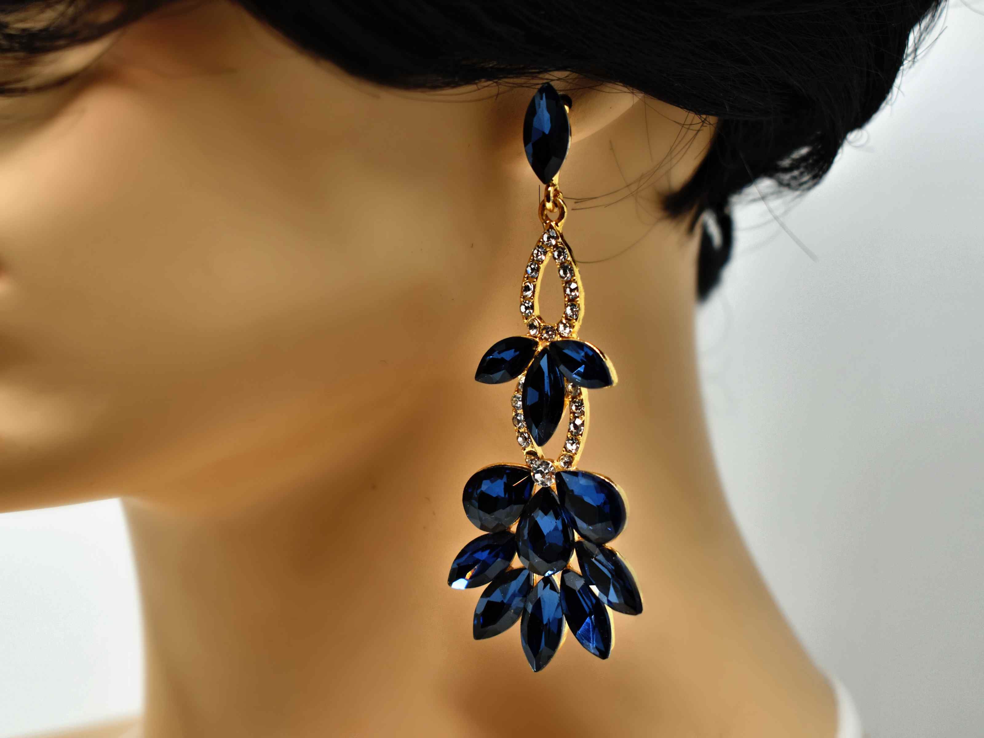 Stunning and beautifully crafted. Our hydrangea gold earrings are a drop dangle earring with big blue sapphire colored stones and smaller clear stones. It is 3 1/2 inches in length with a push back clasp.