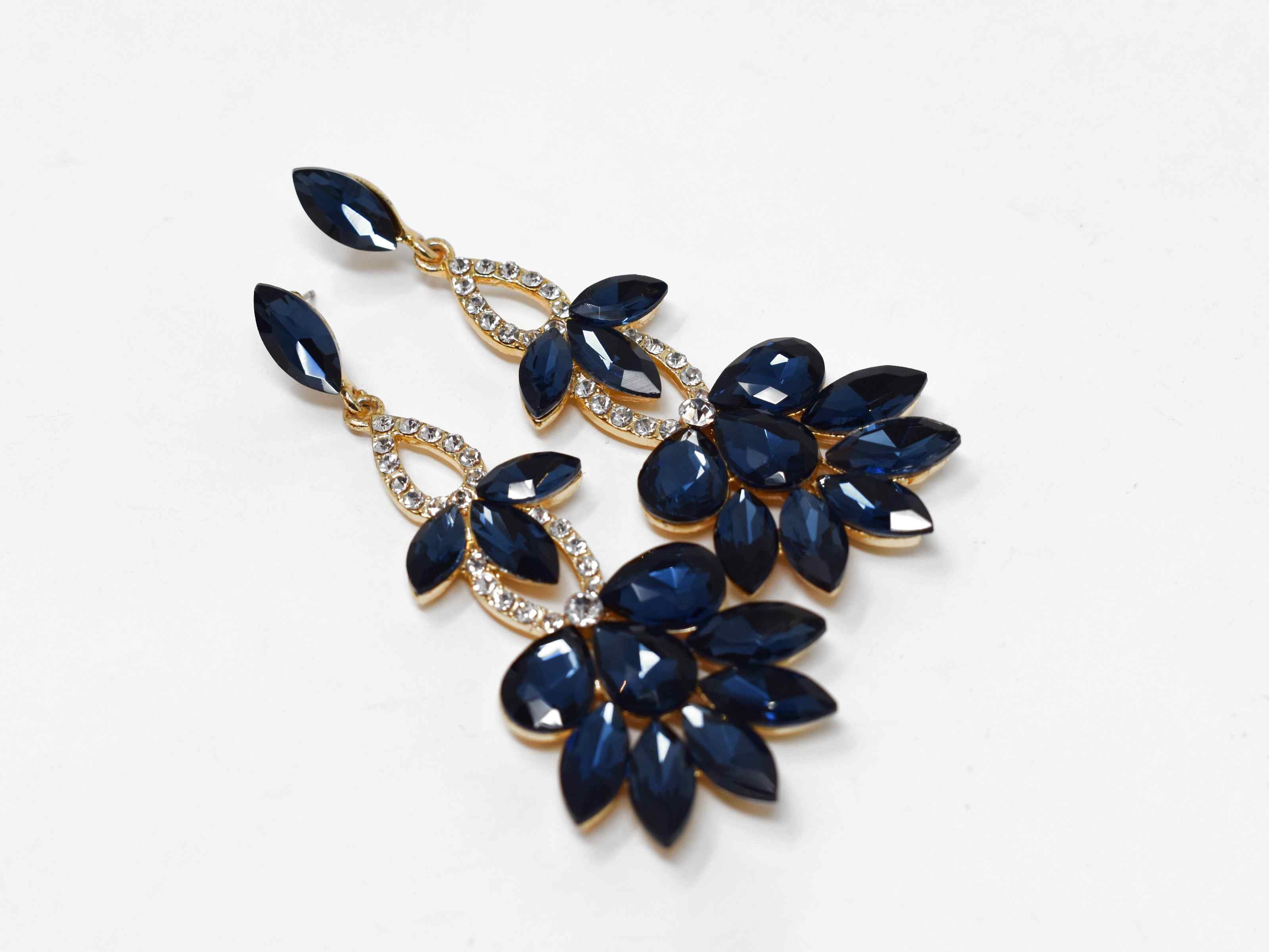 Stunning and beautifully crafted. Our hydrangea gold earrings are a drop dangle earring with big blue sapphire colored stones and smaller clear stones. It is 3 1/2 inches in length with a push back clasp.