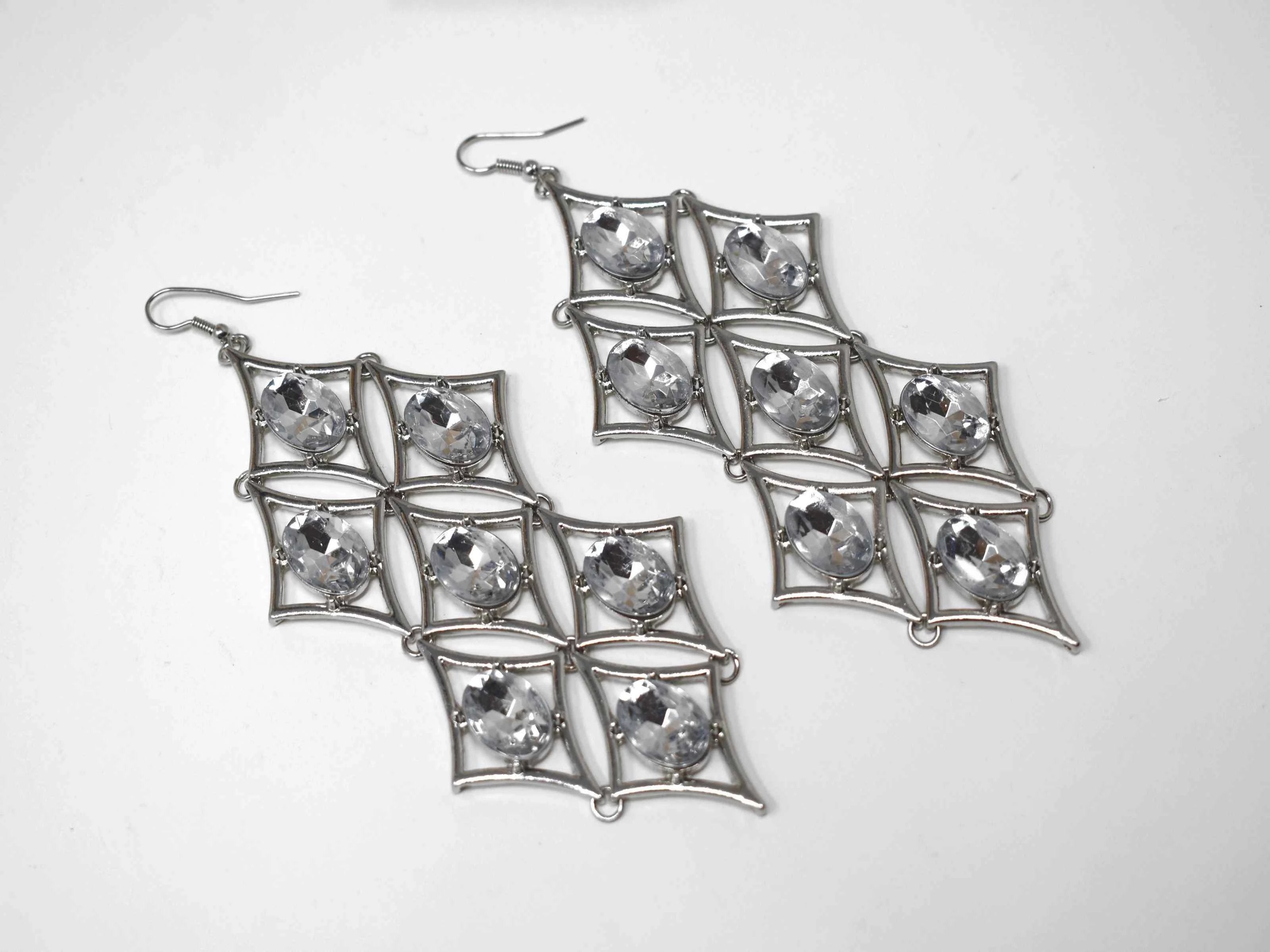 Let our Iris chandelier Silver earrings add a gorgeous glow to any outfit. These chandelier earrings has a diamond shape accented with clear stones. It has fishhook clasp and is about 5 inches in length.