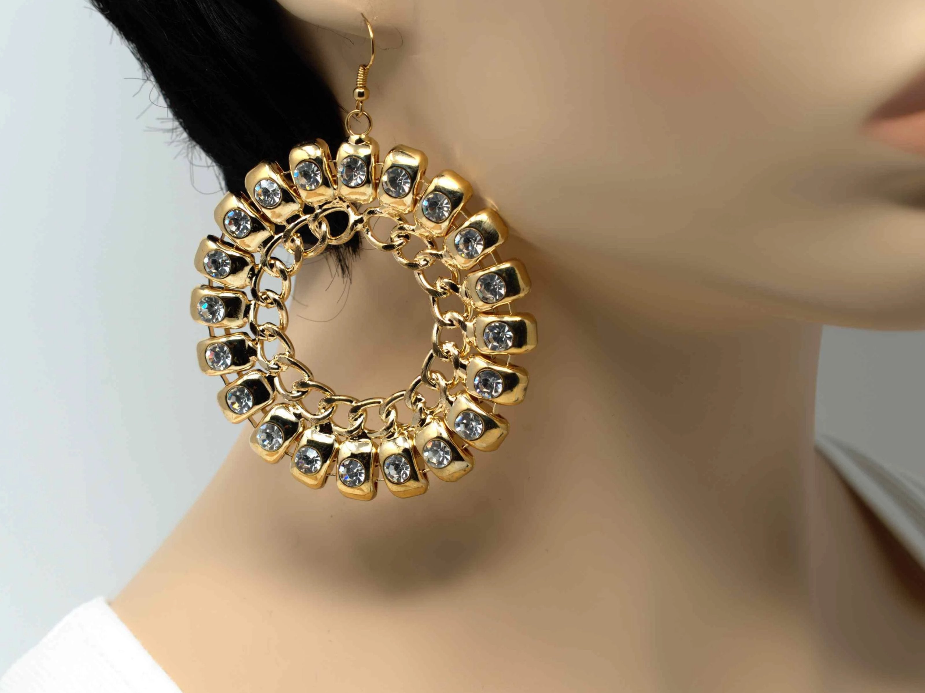 An exquisite gold dangle drop fashion earring with stones and chain accent and a fish hook clasp.