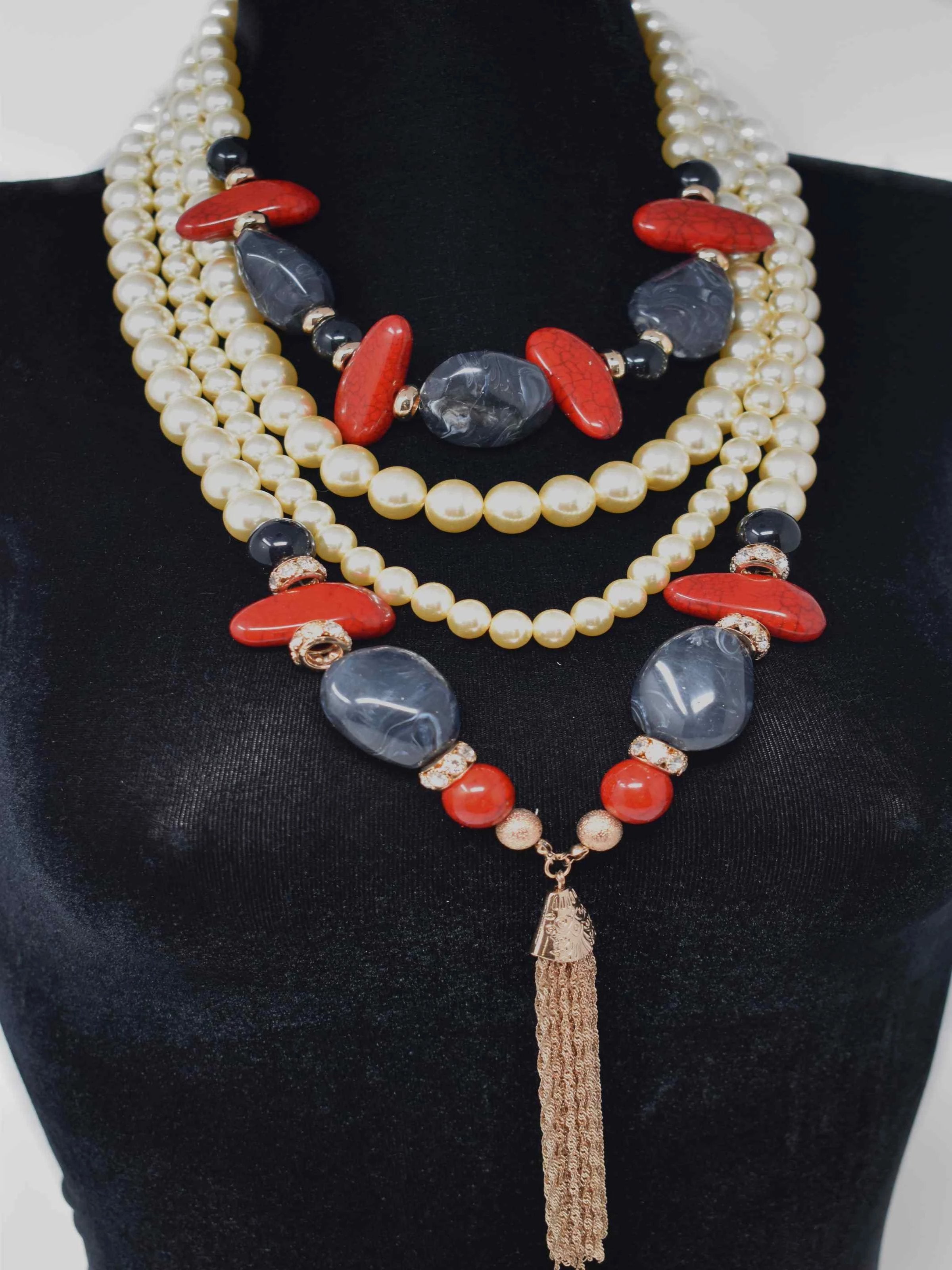 Milla adds a modern twist to a classic set of pearls. This is our long statement pearl layered necklace accented with red and black stones and a gold fringe tassel. It measures around 20" in length and closes with a lobster clasp.