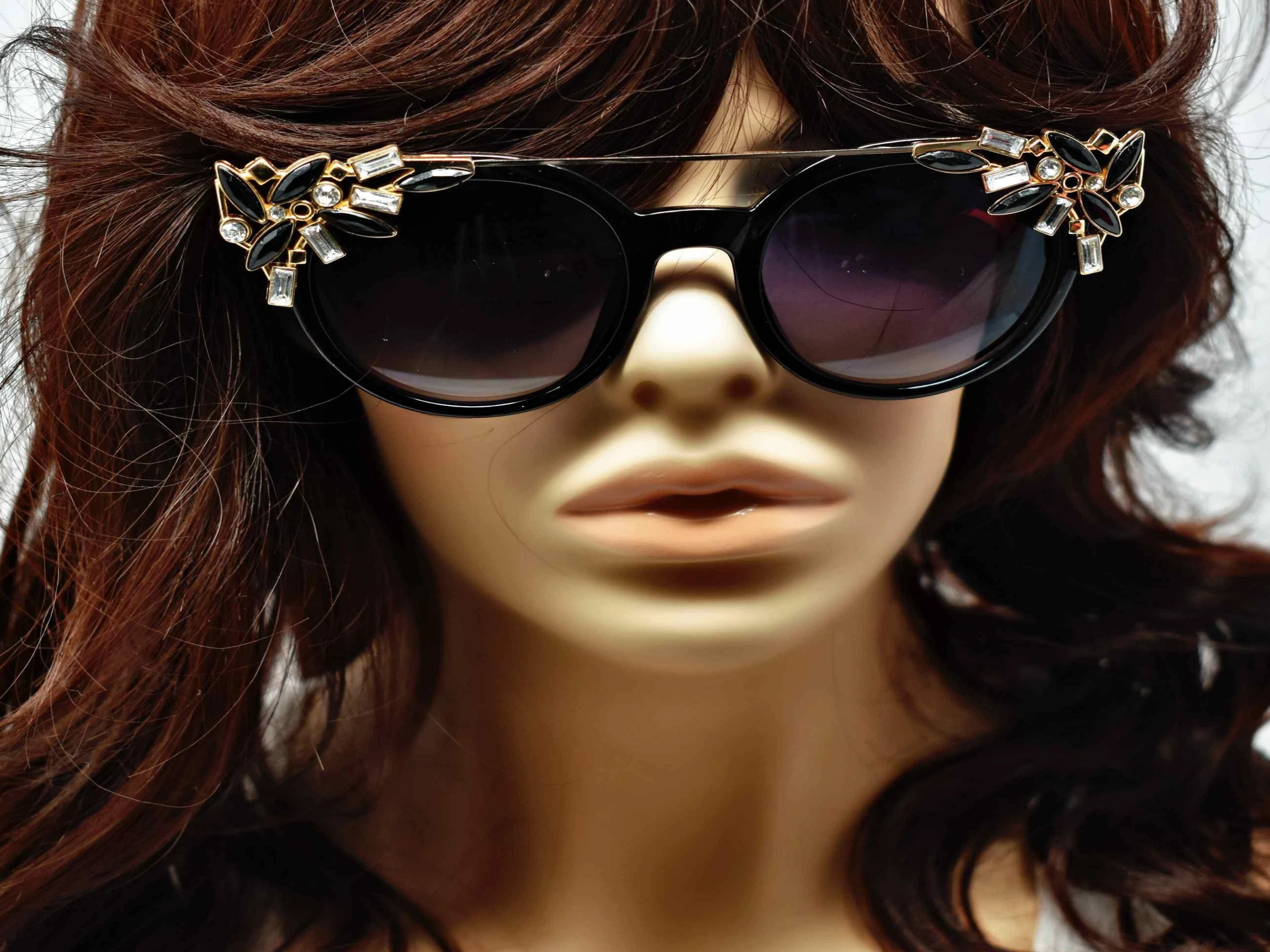 Trend setter and attention getter is what they will call you in these Pansy Black sunglasses with a sleek gold trim adorned in clear and black gems, in a pantos style frame.
