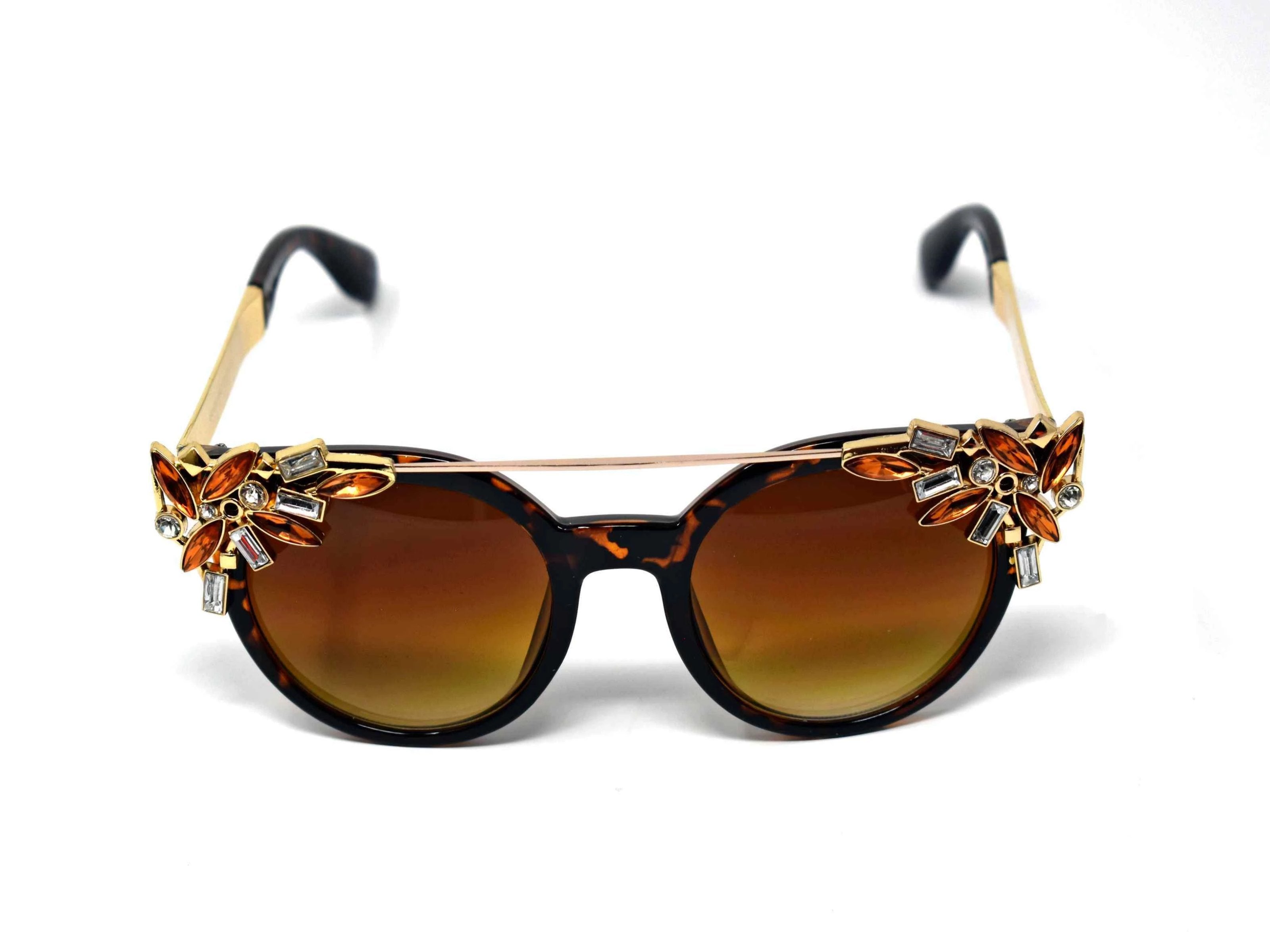Trend setter and attention getter is what they will call you in these Pansy Leopard sunglasses with a sleek gold trim adorned in clear and brown gems, in a pantos style frame.