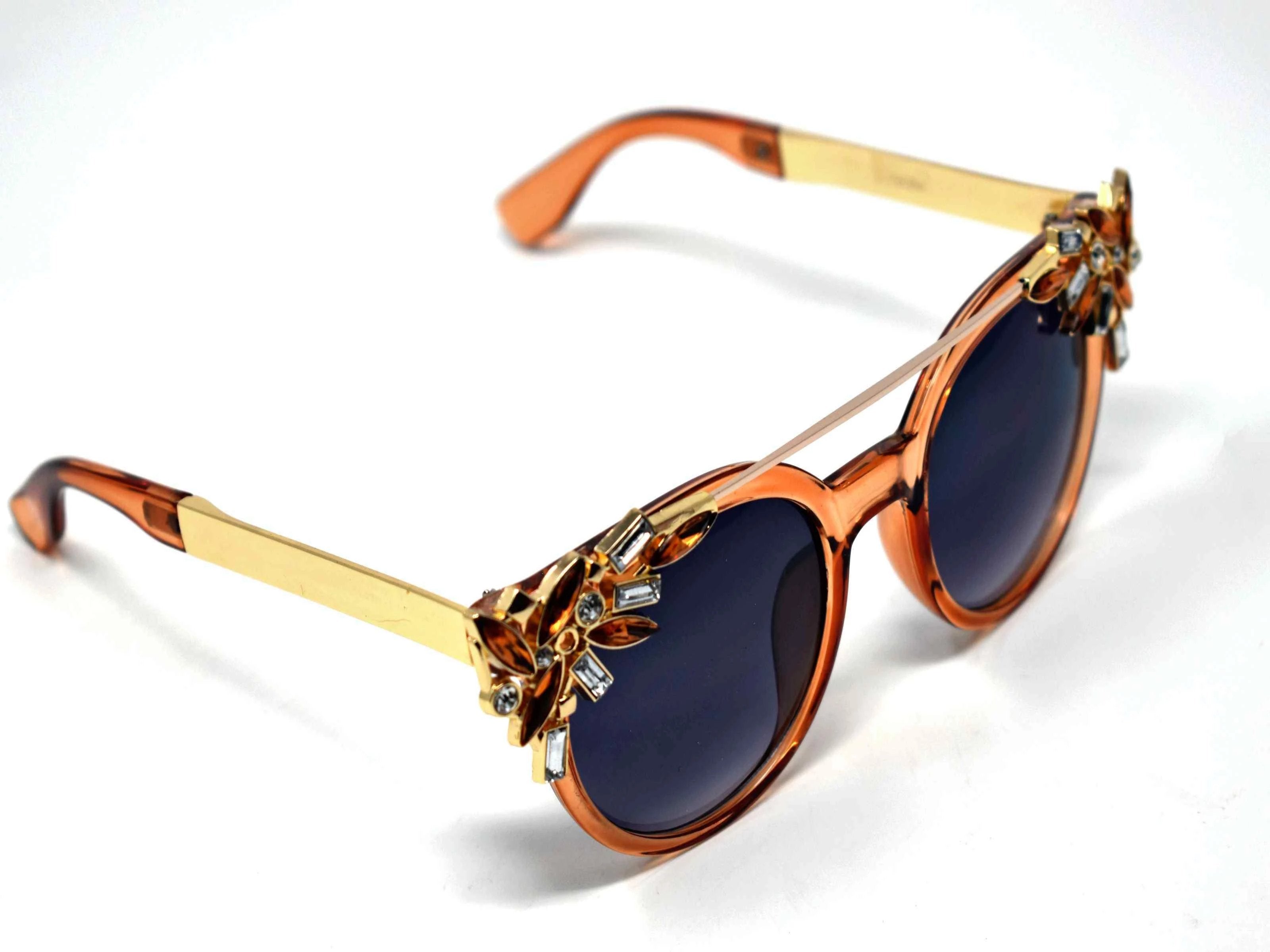Trend setter and attention getter is what they will call you in these Pansy brown sunglasses with a sleek gold trim adorned in brown and clear gems, in a pantos style frame.