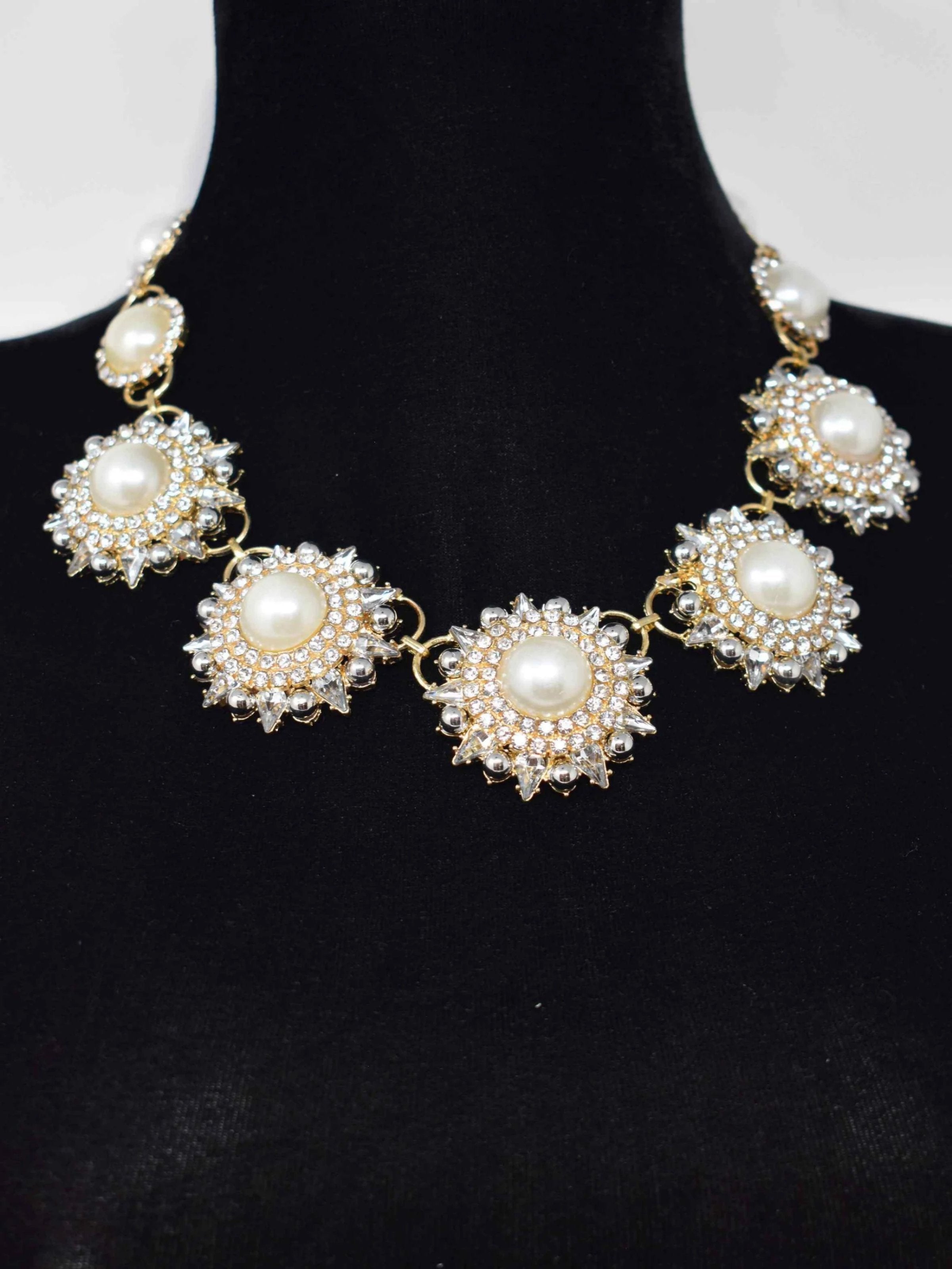 Our Rica statement necklace will add an elegant stylish glow to your outfit. This Gold and pearl floral linked necklace is accented with stones and closes with a lobster clasp. It measures 10 1/2" in length.