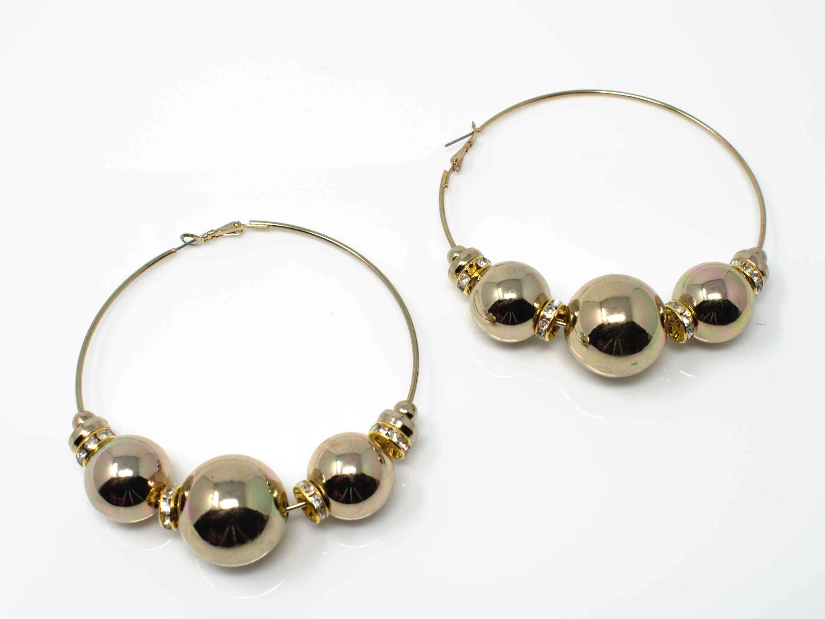A distinctive gold hoop fashion earring with ball and stone accents.