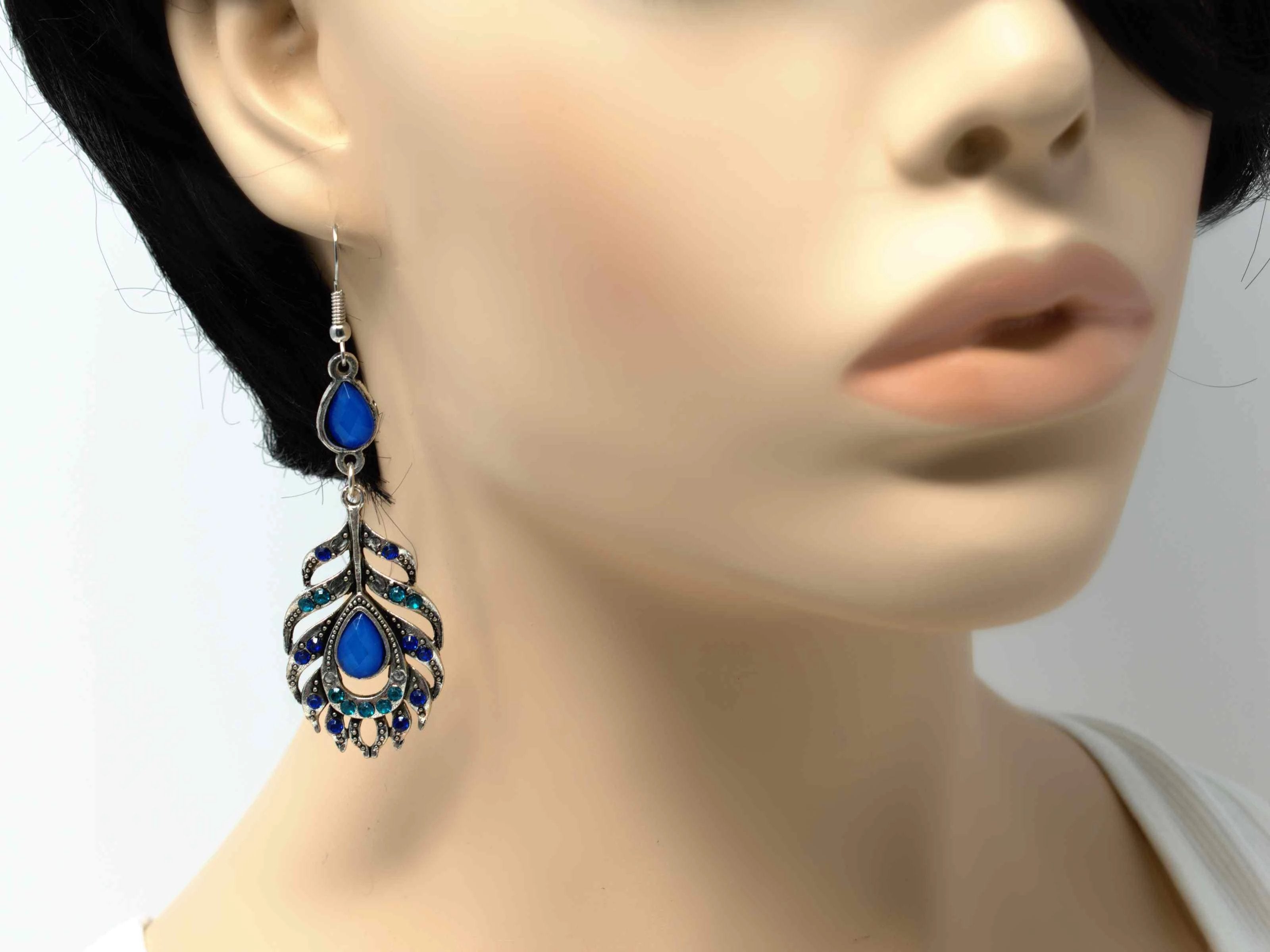 A dainty silver drop dangle feather fashion earring with blue accent stones and a fish hook clasp.
