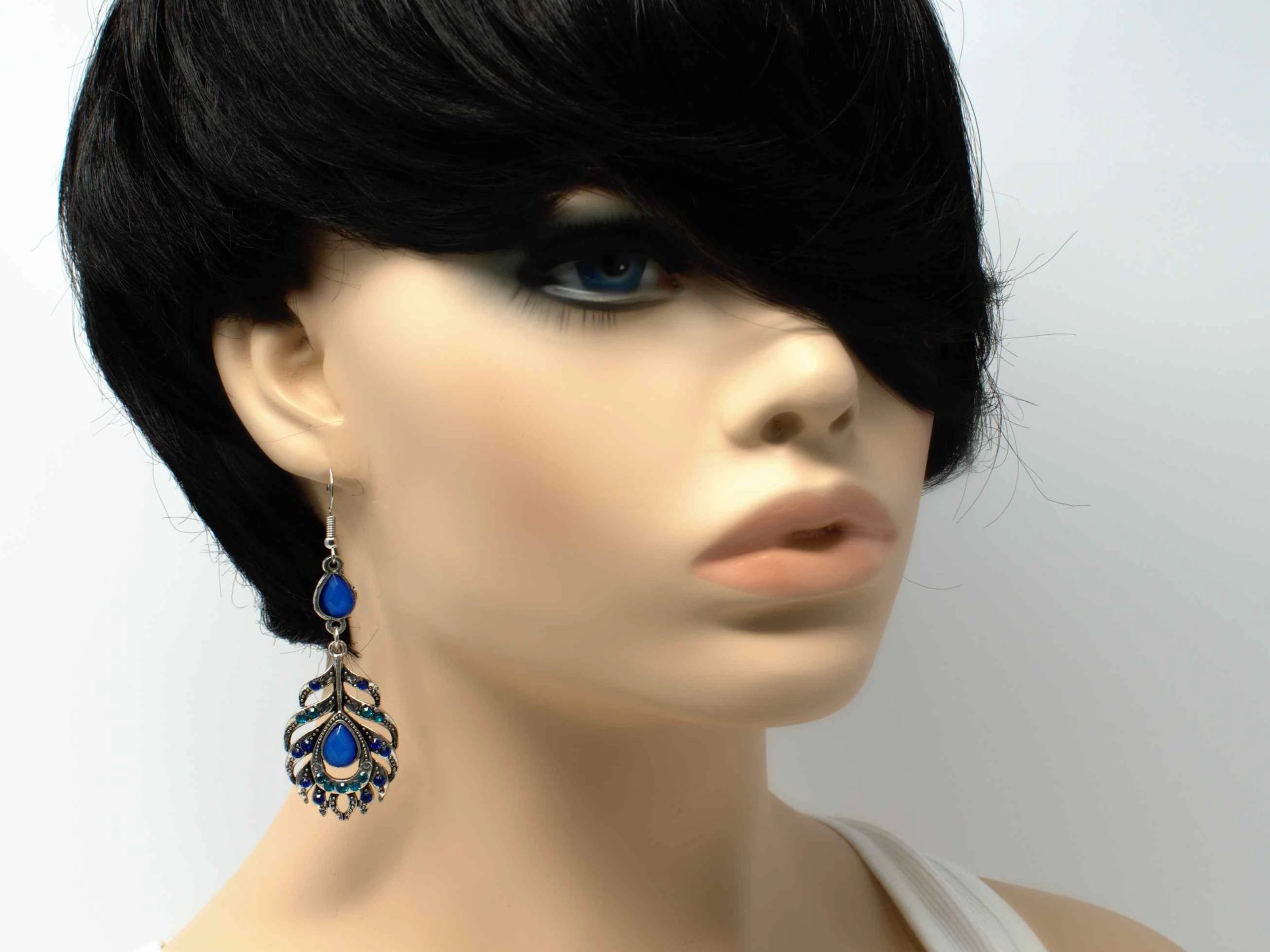 A dainty silver drop dangle feather fashion earring with blue accent stones and a fish hook clasp.